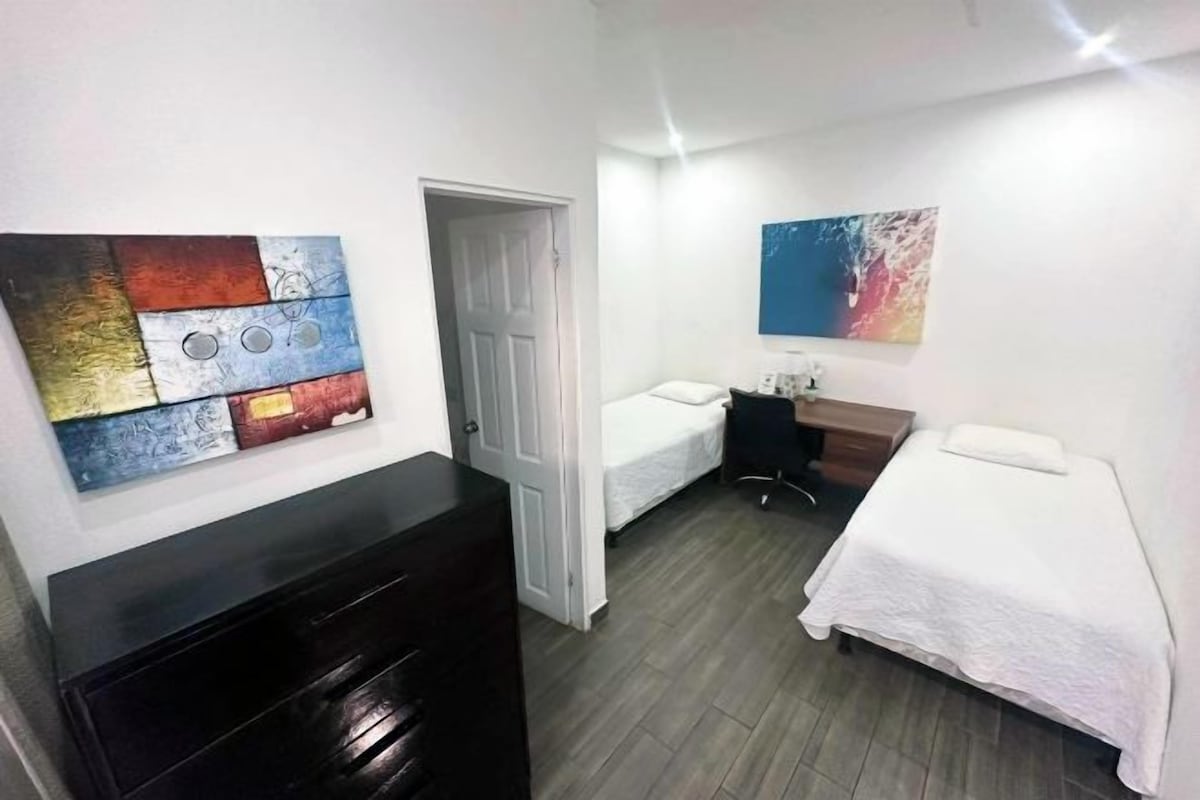 A room with two beds, a desk, and a dresser.