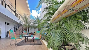 A courtyard with a table and colorful chairs, surrounded by potted plants and a staircase. - Surf Ranch Tamarindo (Tamarindo)