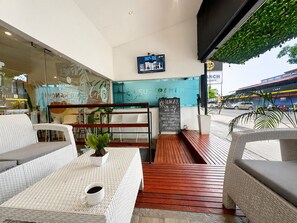 A cafe with wicker furniture, a coffee cup on a table, and a chalkboard menu. - Surf Ranch Tamarindo (Tamarindo)