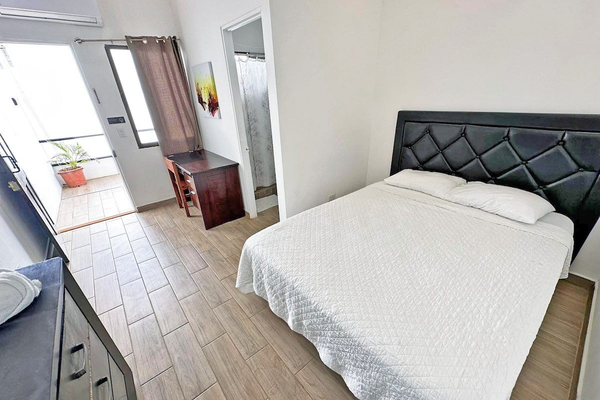 A bedroom with a bed, a desk, and a chair.
