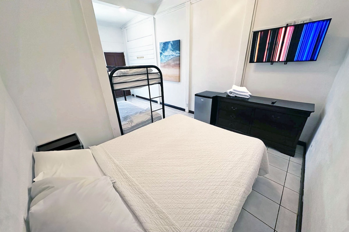 Une chambre d’hôtel avec un lit, un bureau équipé d’un ordinateur, une télévision et un tableau accroché au mur.