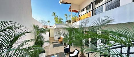 A modern building with a courtyard featuring outdoor seating and palm trees.