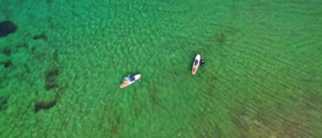 An aerial view of a beach with two surfboards floating on the water.