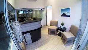 A modern living room with a curved black coffee table, two beige armchairs, a small black side table with a plant, and a painting on the wall. - Surf Ranch Tamarindo (Tamarindo)