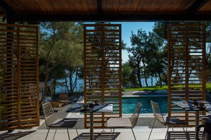 A poolside area with wooden partitions, outdoor seating, and a view of the water. - Elies 33 Bio Retreat - Adults Only (Kassandra)