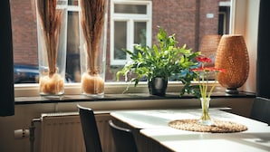 A window sill with two tall glass vases containing dried plants, a potted plant with green leaves and red flowers, and a woven lamp. - B&b De Hofnar Roermond (Roermond)