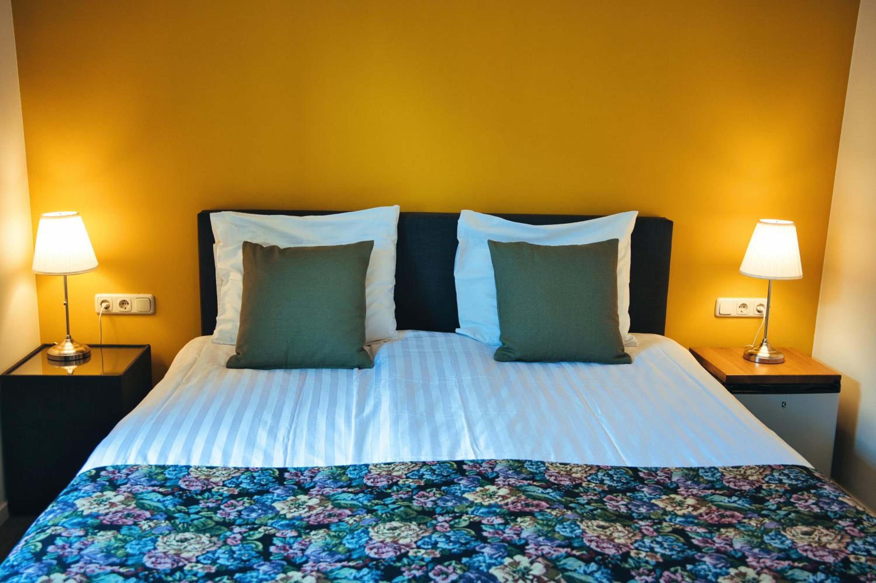Een hotelkamer met een bed, twee nachtkastjes, twee lampen en een bloemenbedekking.