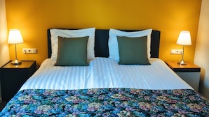 A hotel room with a bed, two nightstands, two lamps, and a floral bedspread. - B&b De Hofnar Roermond (Roermond)