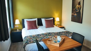 A hotel room with a bed, two bedside lamps, a wooden side table with a tray, and a painting on the wall. - B&b De Hofnar Roermond (Roermond)