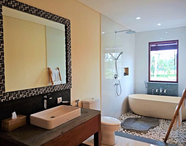 A modern bathroom with a large mirror, a sink, a toilet, and a bathtub. -  DLobong Suites Ubud (Ubud)