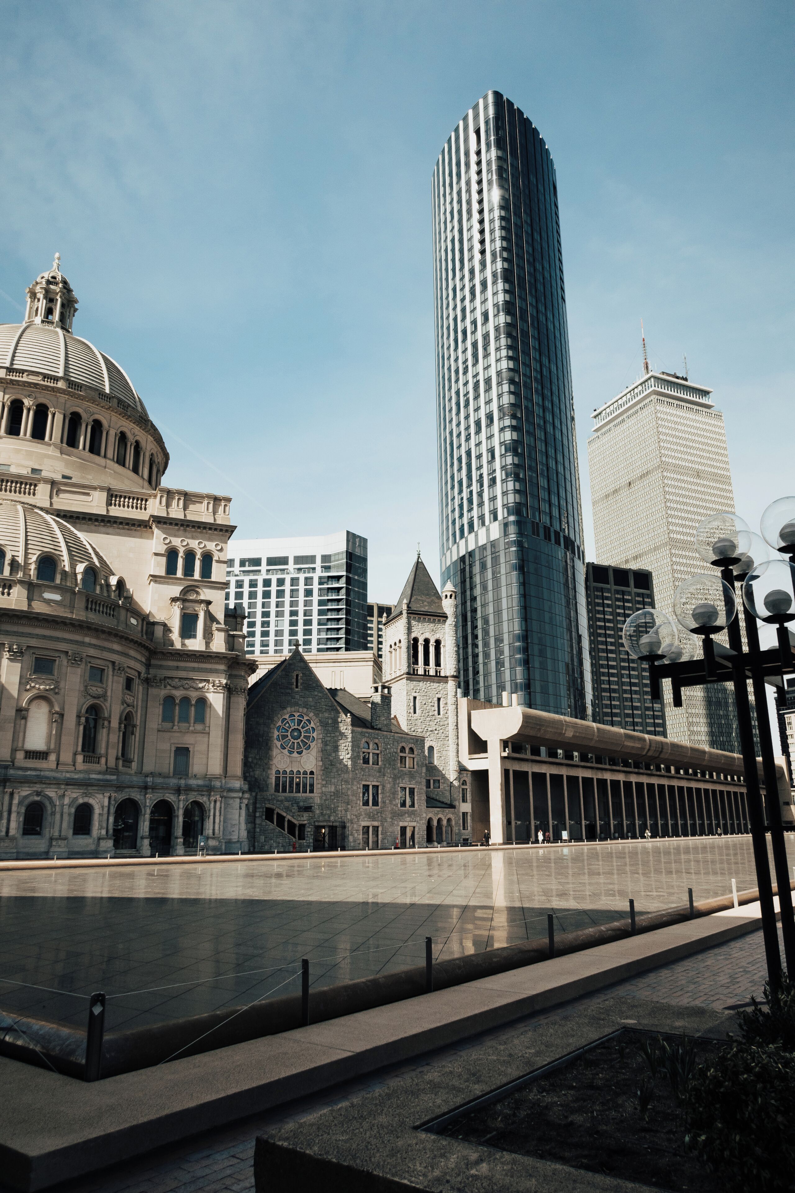 Paisagem urbana com arquitetura histórica e moderna, incluindo um edifício com cúpula e um arranha-céu imponente.