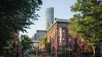 A street view with a mix of modern and traditional buildings, including a tall skyscraper and older brick structures.