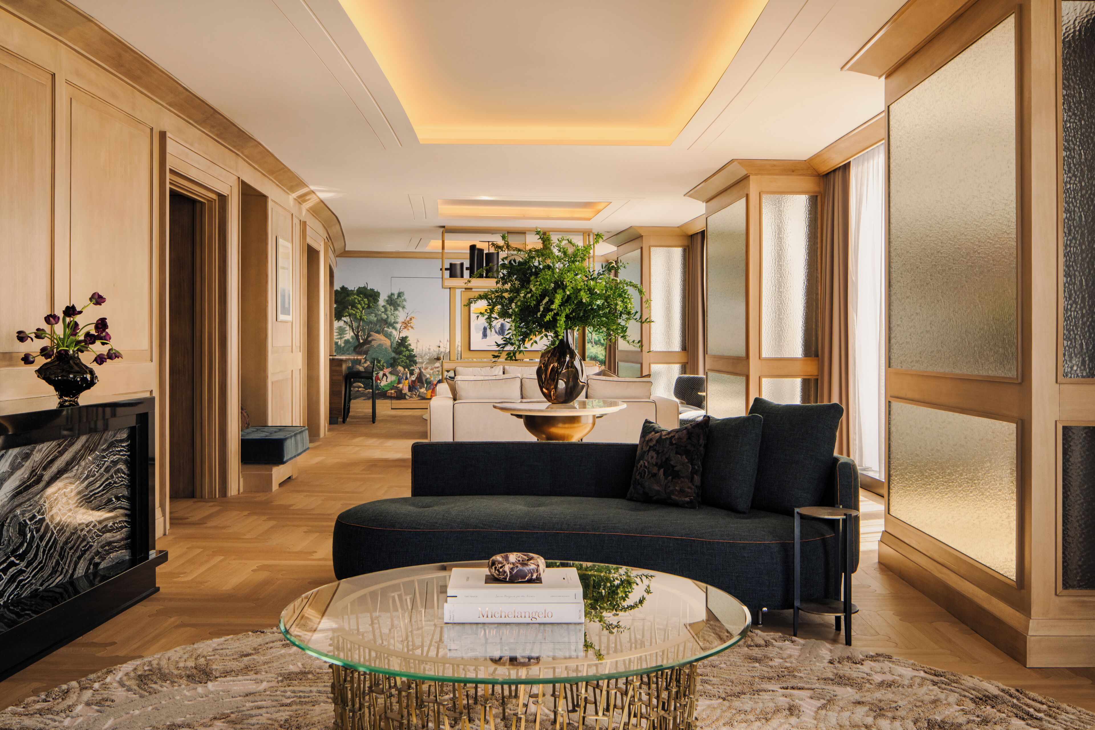 A modern living room with a glass coffee table, a sofa, and a large window.