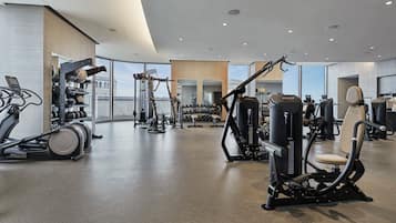 Un gimnasio moderno con diverso equipo de ejercicio, ventanas amplias y un diseño limpio y espacioso.
