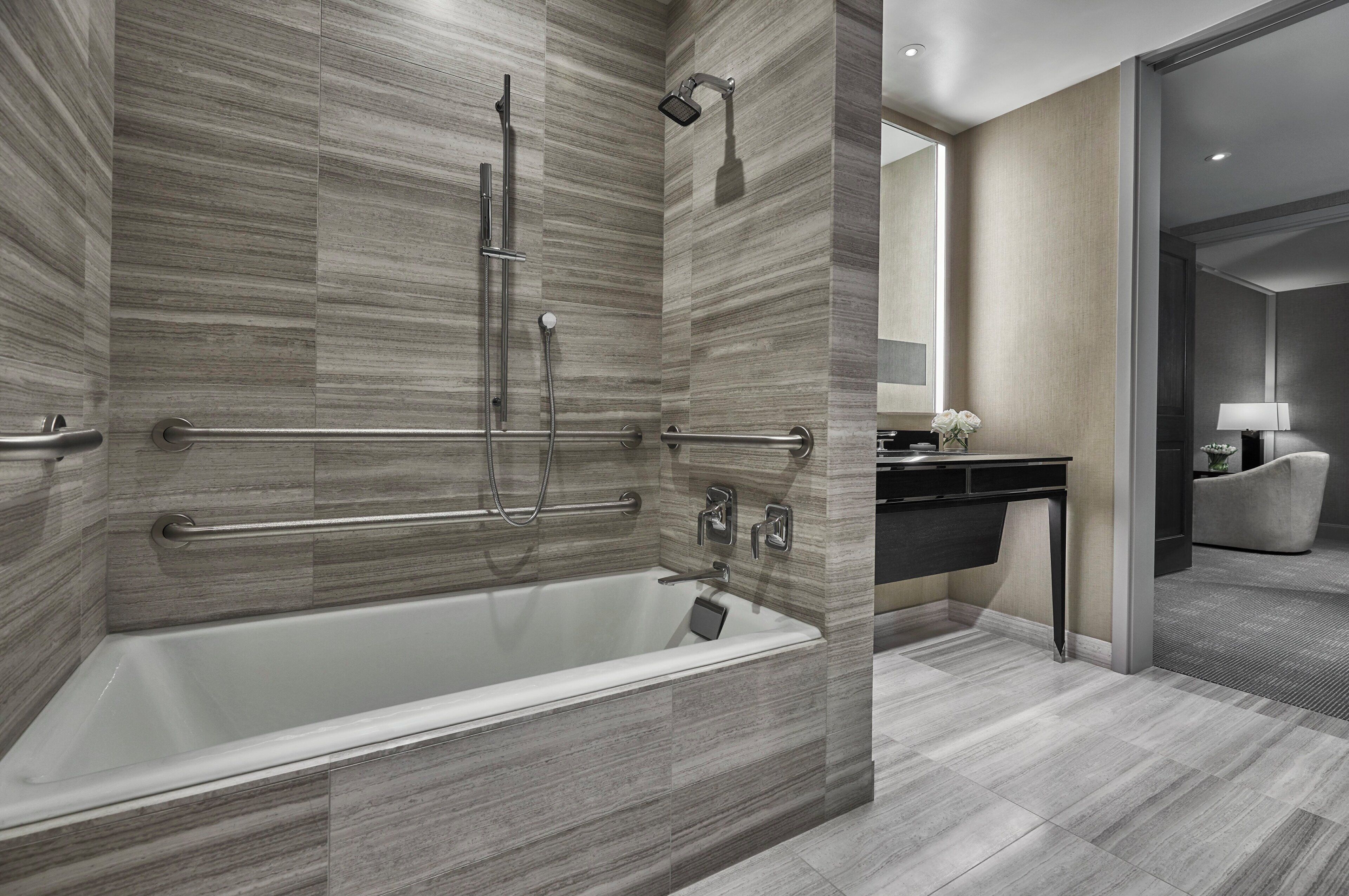A modern bathroom with a walk-in bathtub, grab bars, and a showerhead.