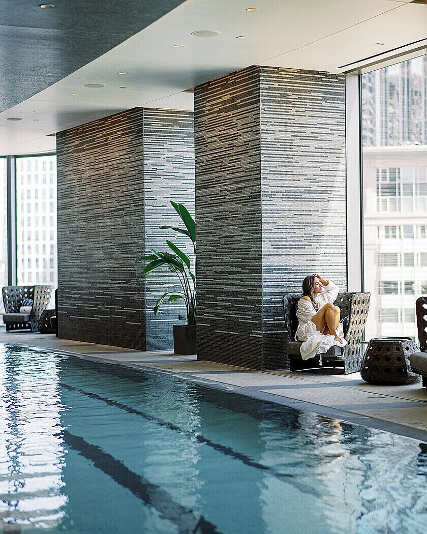 A pool area with a seating area, a large window, and a tall pillar.