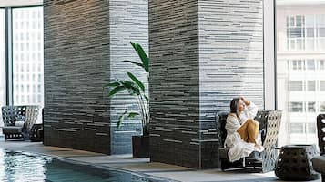 A pool area with a seating area, a large window, and a tall pillar.