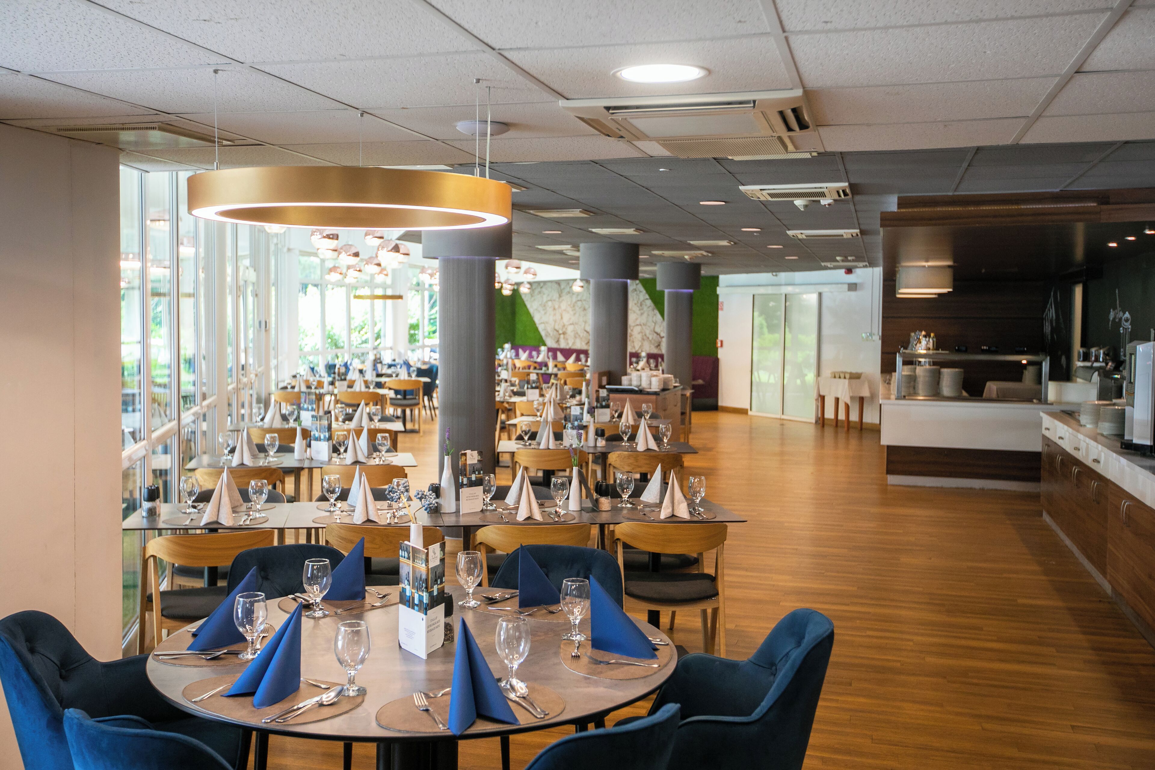 Un restaurant spacieux doté de nombreuses tables, de chaises et d’une cuisine moderne.