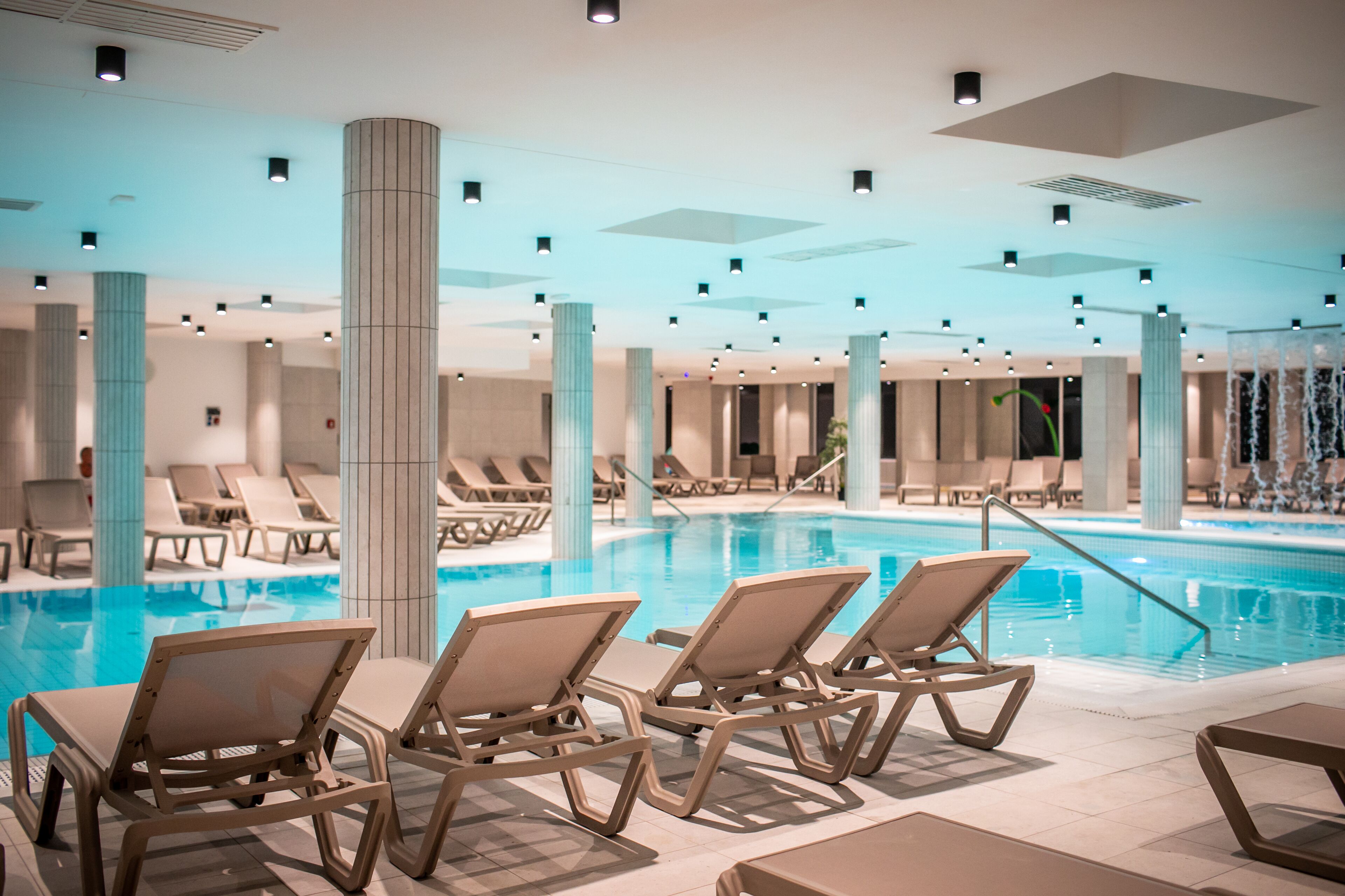 Ein Innenpool mit Liegestühlen und einem modernen Deckenstil.