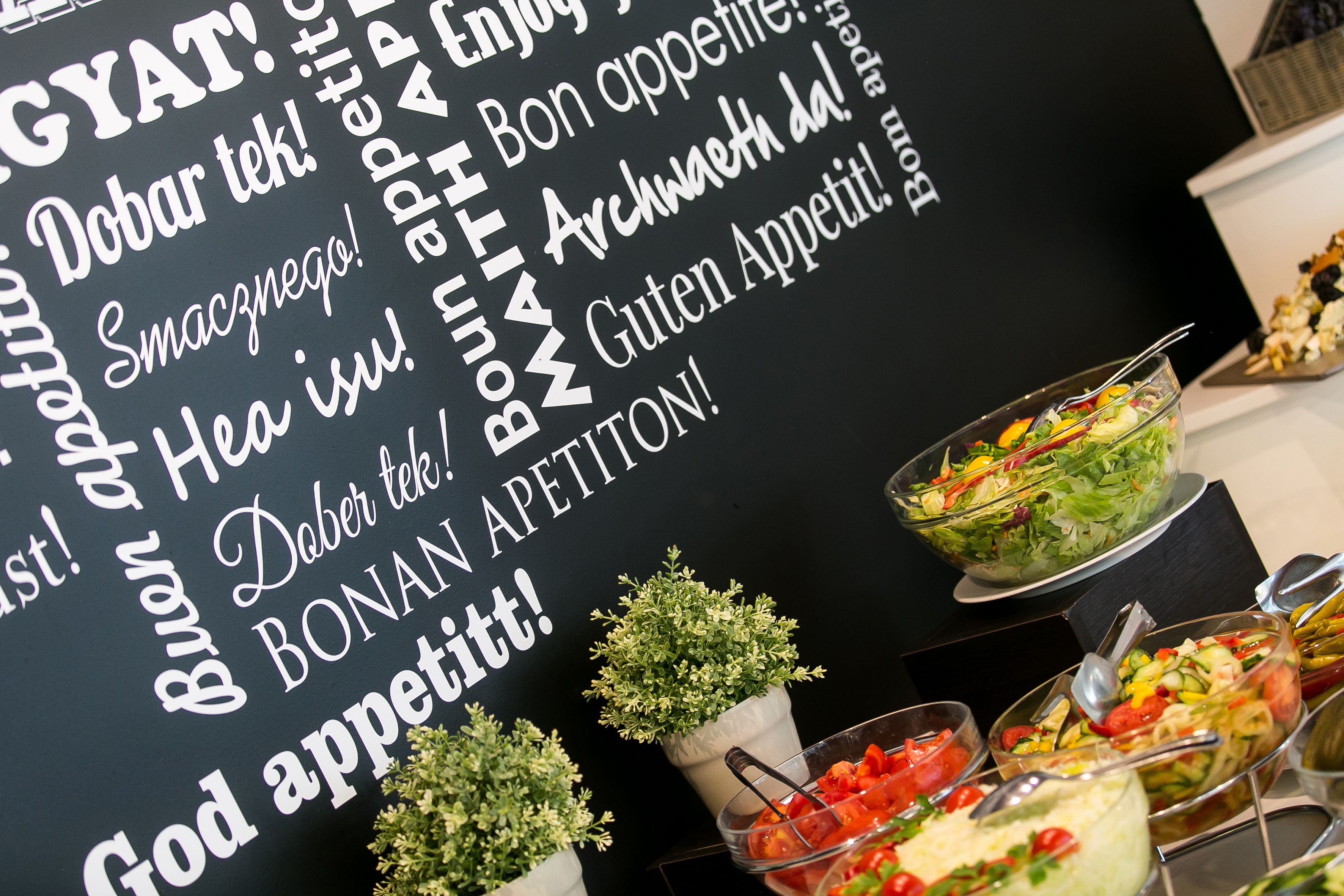 A buffet with various dishes and a sign with text in a foreign language.