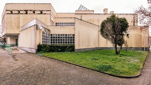 Een gebouw met een platte gevel, een geplaveid binnenhof en een boom.
