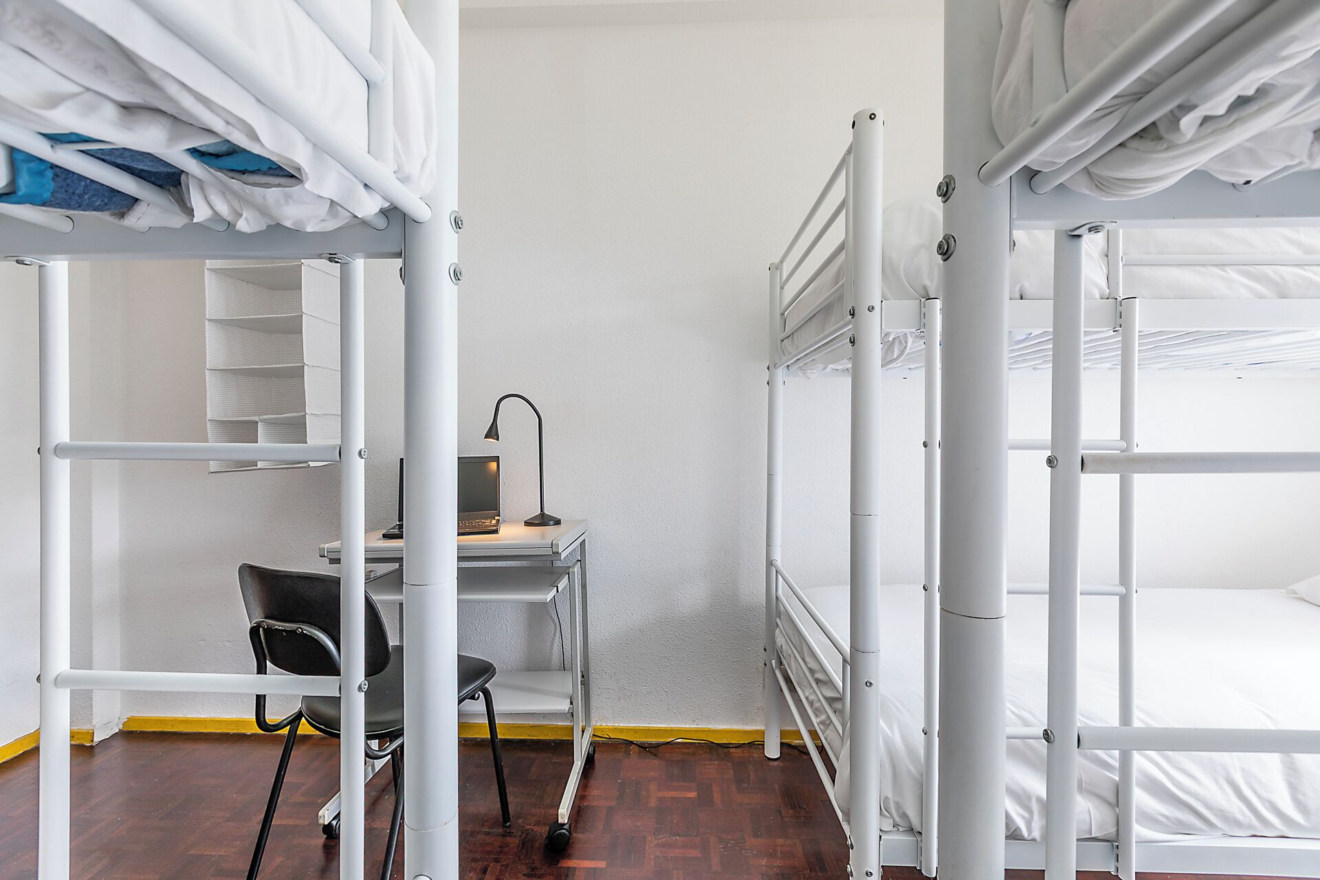 Un dormitorio con literas, un escritorio con silla y una computadora portátil.