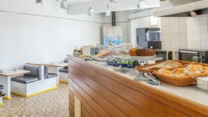 Een ontbijtbuffet met diverse gerechten, een koffiehoek en zithoeken.