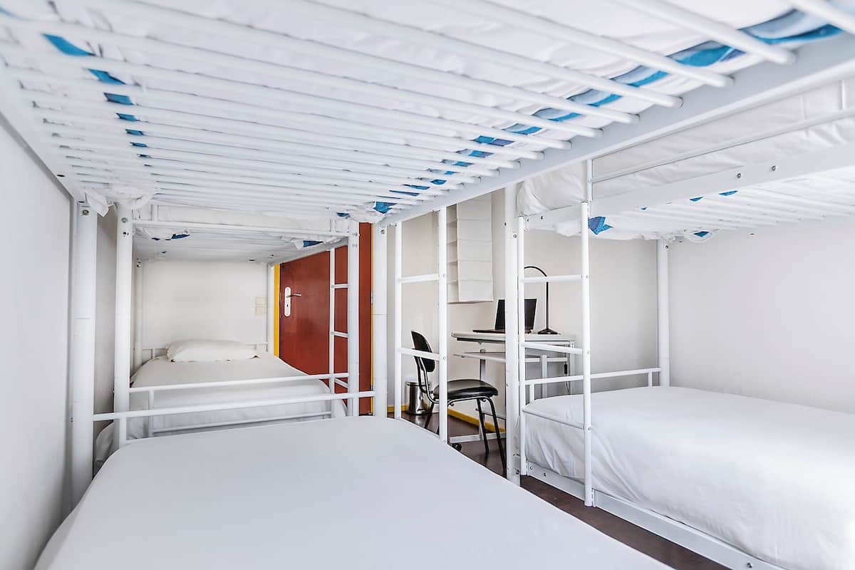 A bunk bed room with a desk, chair, and a computer.