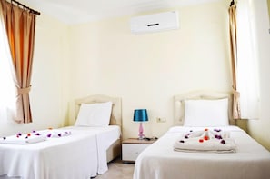 A hotel room with two beds, a bedside table with a lamp, and a window with curtains. - 2 Bedroom Apartment Sea View 9 by Likya Global (Milas)