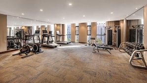 A spacious gym with cardio machines, weightlifting equipment, and a mirror wall. - Zhenbao Holiday Hotel (Nanjing Olympic Sports Center) (Nanjing)