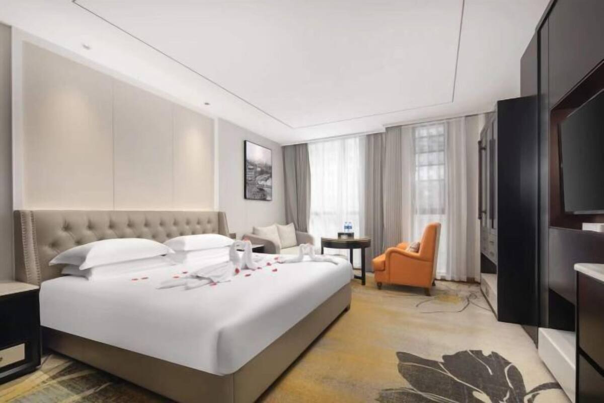 Een hotelkamer met een groot bed, een televisie, een tafeltje en een stoel.