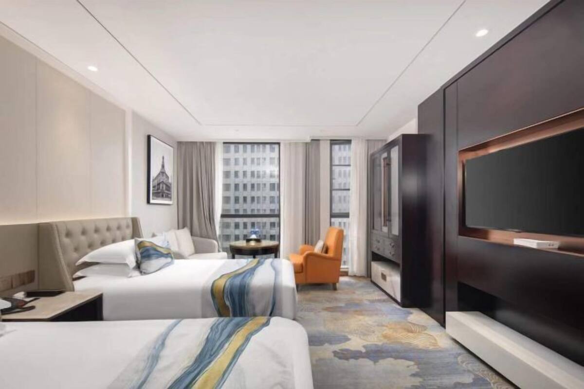 Een hotelkamer met twee bedden, een televisie, een klein tafeltje en een stoel.