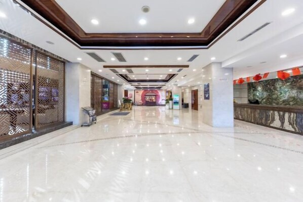 A spacious lobby with a polished marble floor, a reception desk, and a decorative wall with a geometric pattern. - Zhenbao Holiday Hotel (Nanjing Olympic Sports Center) (Nanjing)