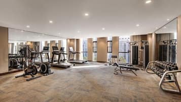 A spacious gym with cardio machines, weightlifting equipment, and a mirrored wall.