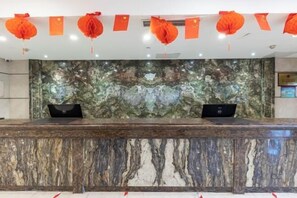 A reception desk with two laptops, a marble wall, and red decorations. - Zhenbao Holiday Hotel (Nanjing Olympic Sports Center) (Nanjing)