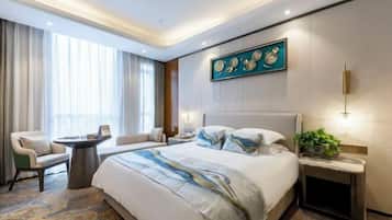 A hotel room with a large bed, a bedside table, a chair, a desk, and a window with curtains.