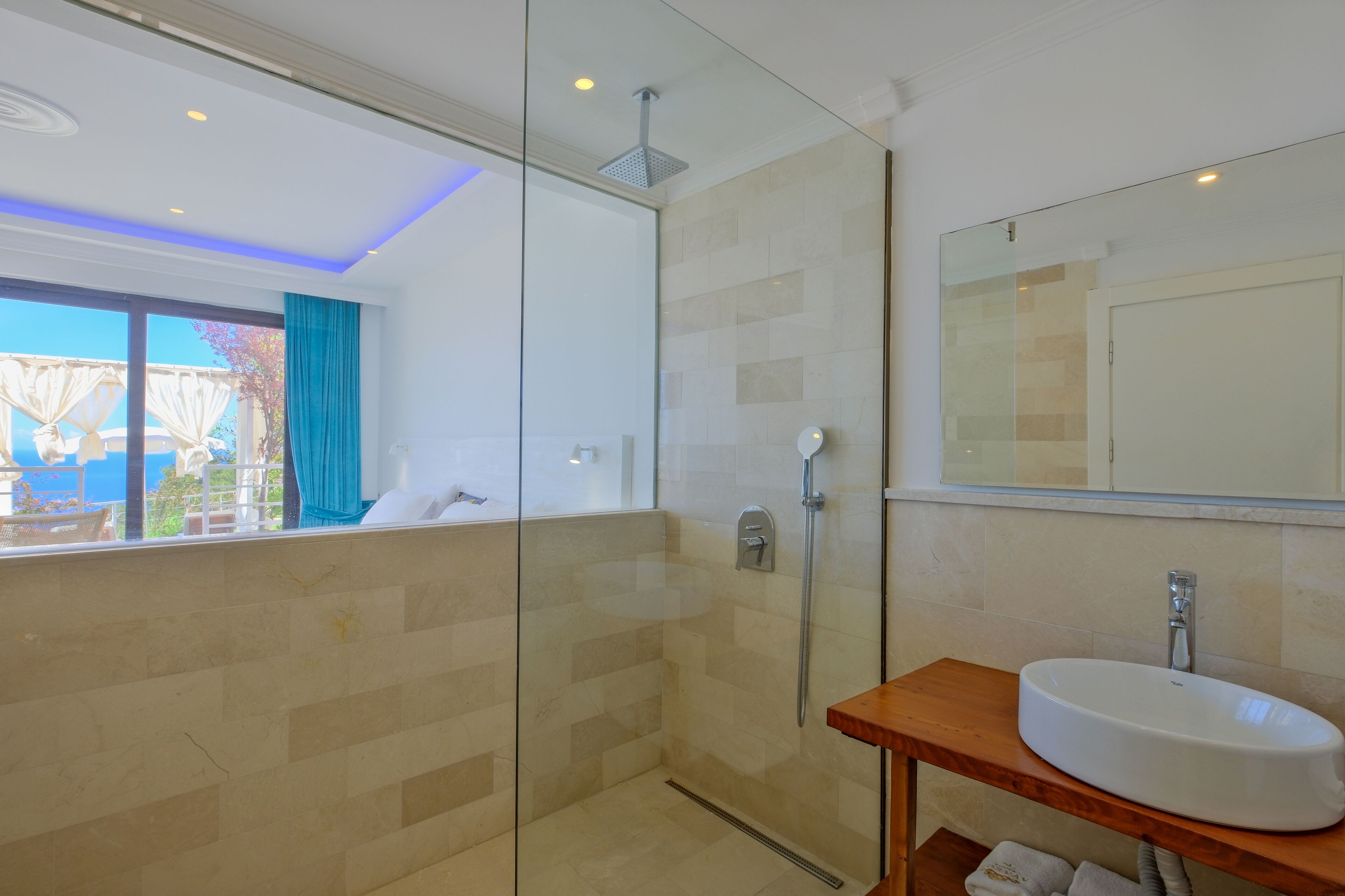 Un baño moderno con cabina de ducha de vidrio, tocador de madera y un espejo grande.