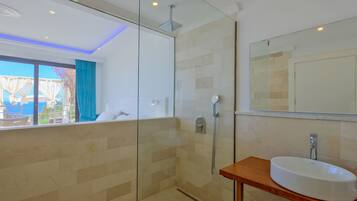 Un baño moderno con cabina de ducha de vidrio, tocador de madera y un espejo grande.