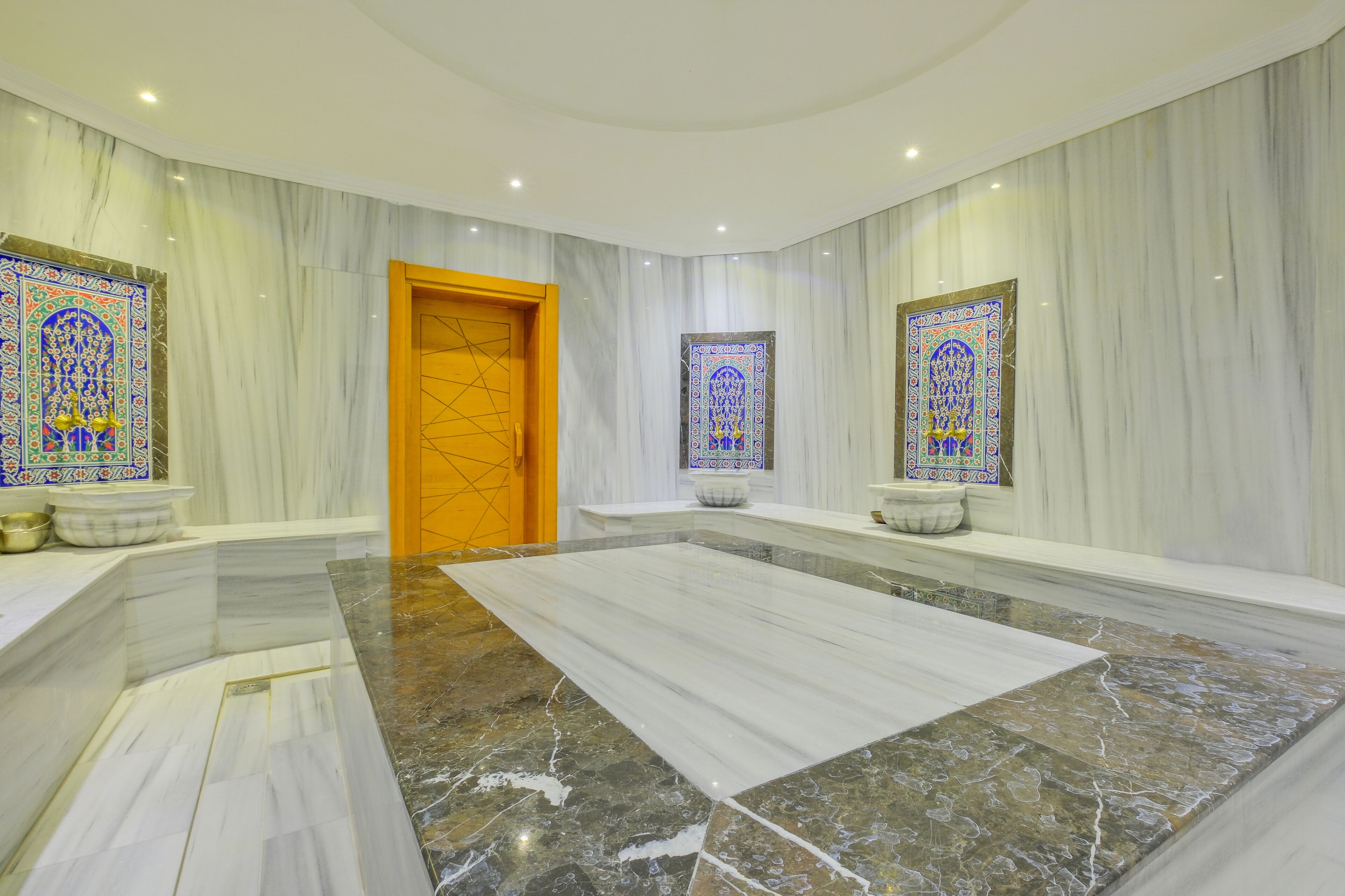 A spacious lobby with marble flooring, a central reception desk, and two ornate stained glass windows.