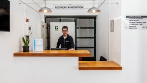 Un comptoir d’accueil avec une pancarte indiquant « Réception » et une liste des services proposés, notamment « Service de repas », « Bar » et « Chambres ».