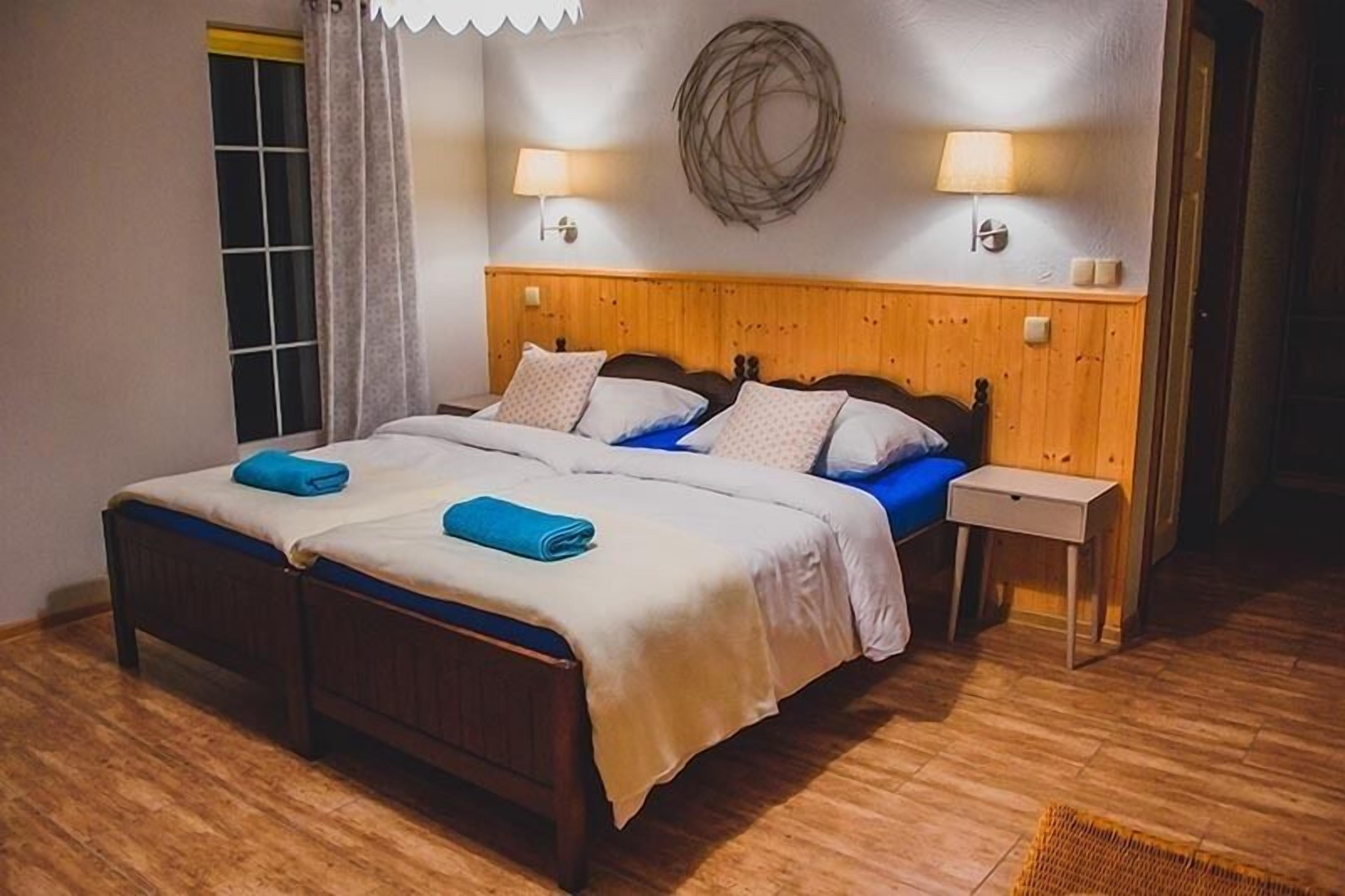 A double bed with a wooden headboard, two bedside tables, and a wall-mounted lamp.