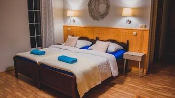 A double bed with a wooden headboard, two bedside tables, and a wall-mounted lamp.