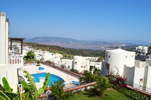 A resort with a swimming pool, white buildings, and a view of the landscape.
