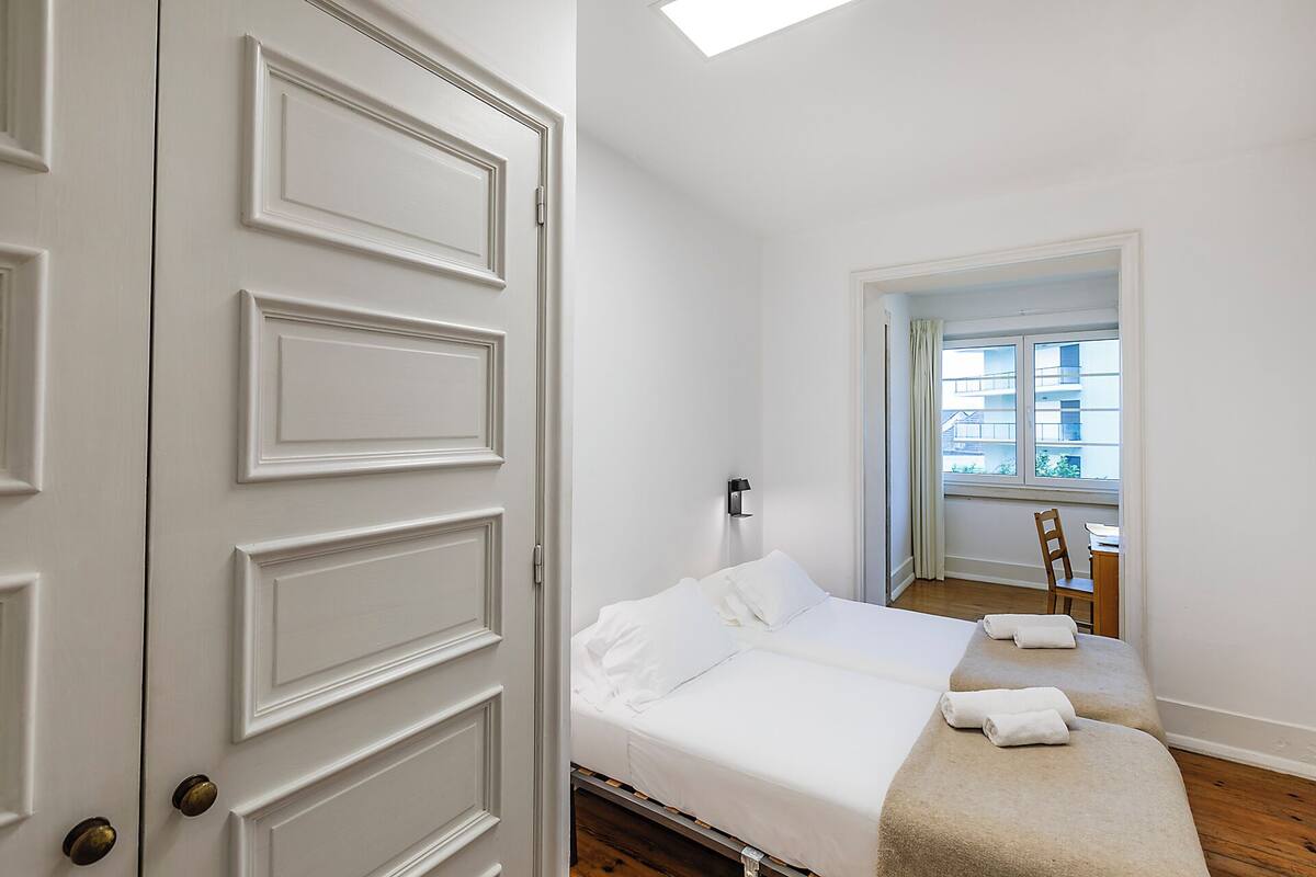 Une chambre à coucher avec un lit, une chaise, une fenêtre et une porte.