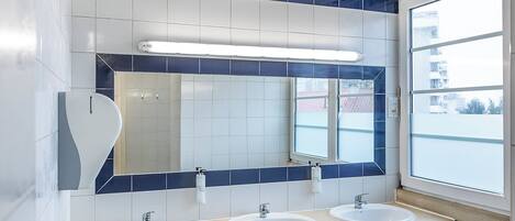 A bathroom with three sinks, a mirror, and a window.