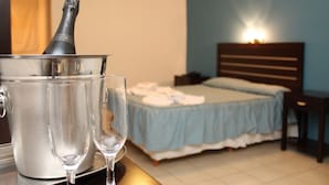 A room with a bed, a bedside table, a nightstand, and a wall-mounted lamp.