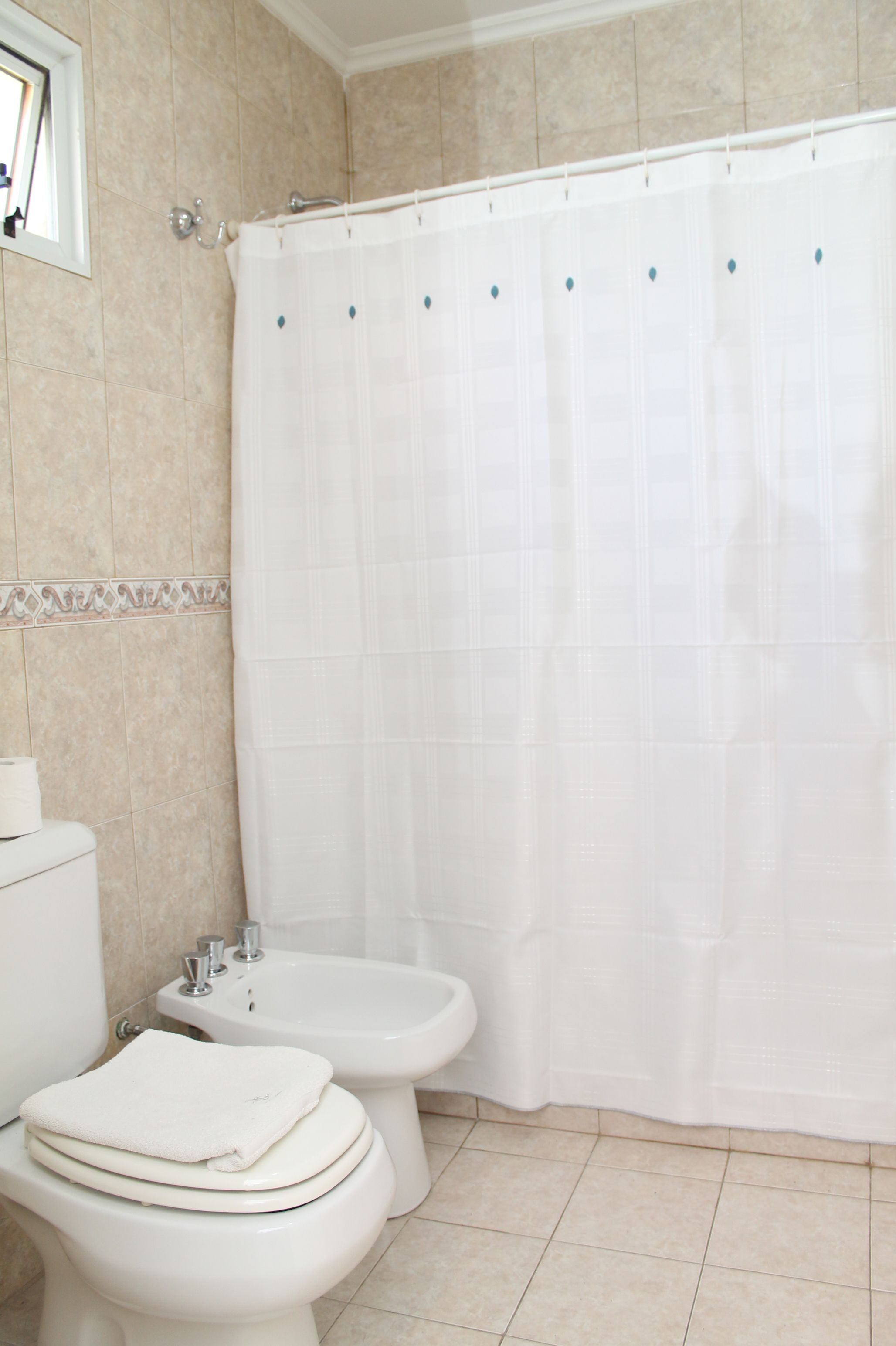 Un baño con inodoro, bidé y cortina de ducha.