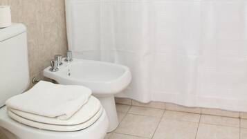 Un baño con inodoro, bidé y cortina de ducha.