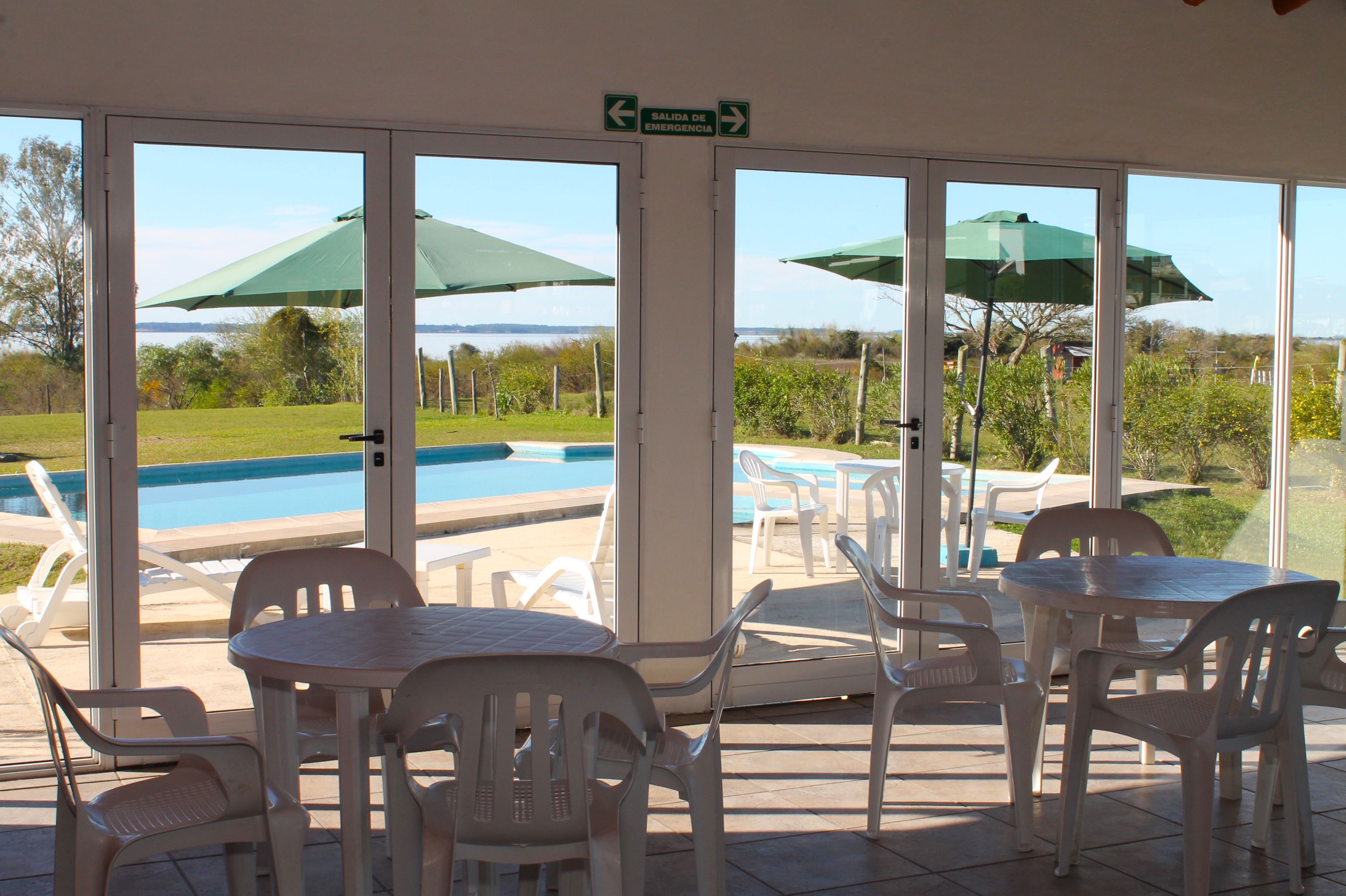 A poolside area with chairs and tables, a pool, and a view of the landscape.