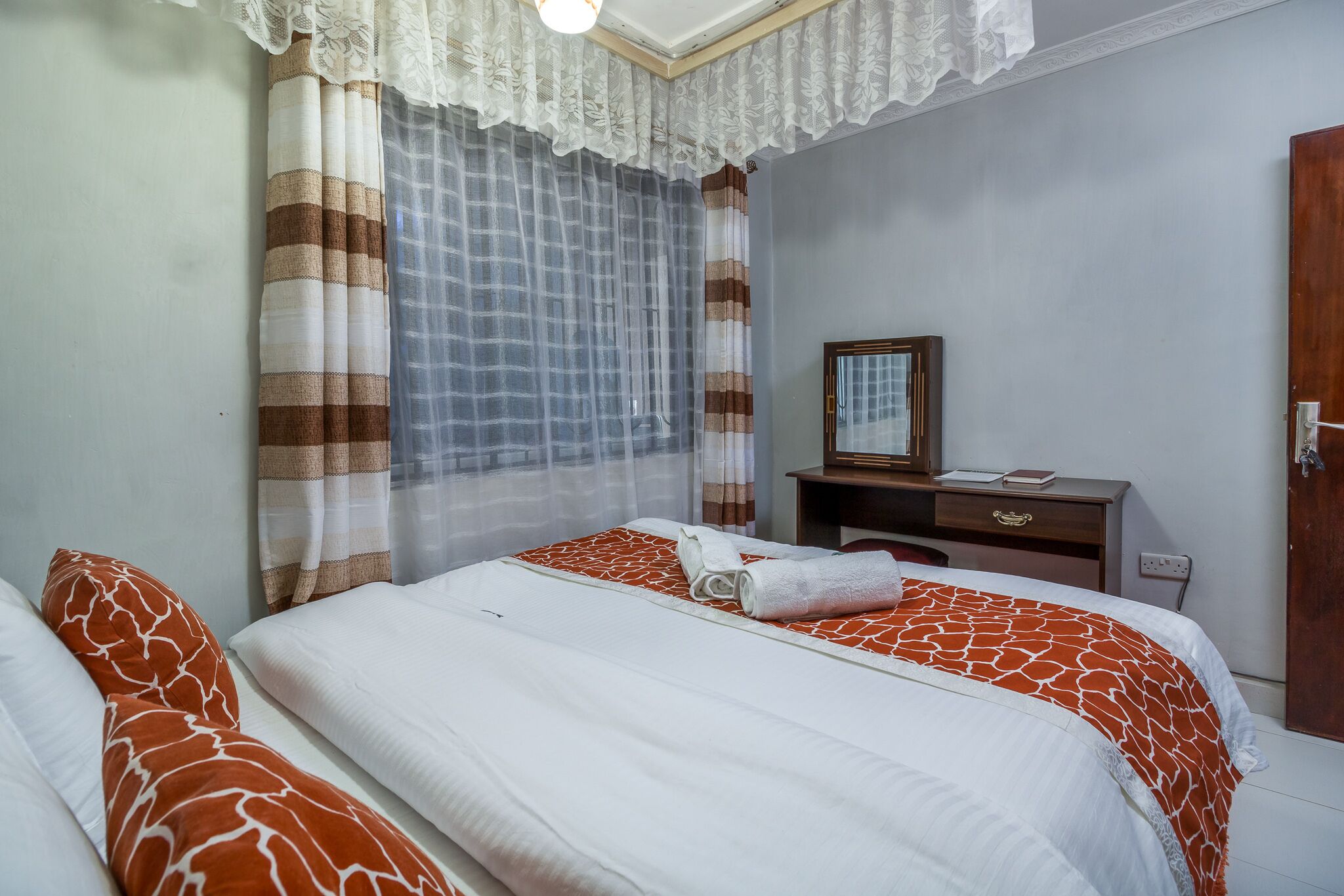 Une chambre d’hôtel avec un lit, un bureau, un miroir et une porte.